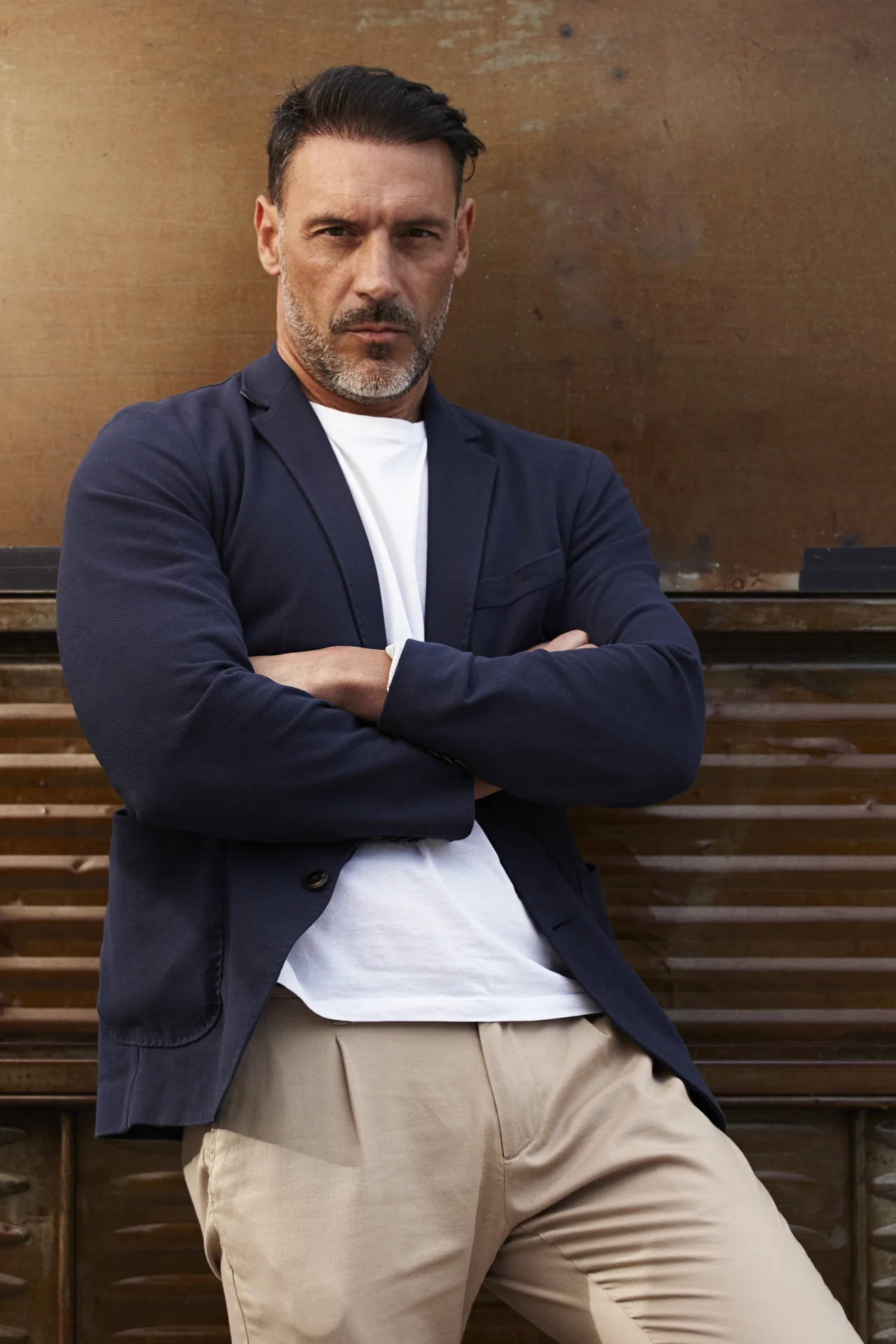 middle aged man wearing leaning against rusty colored background scaled