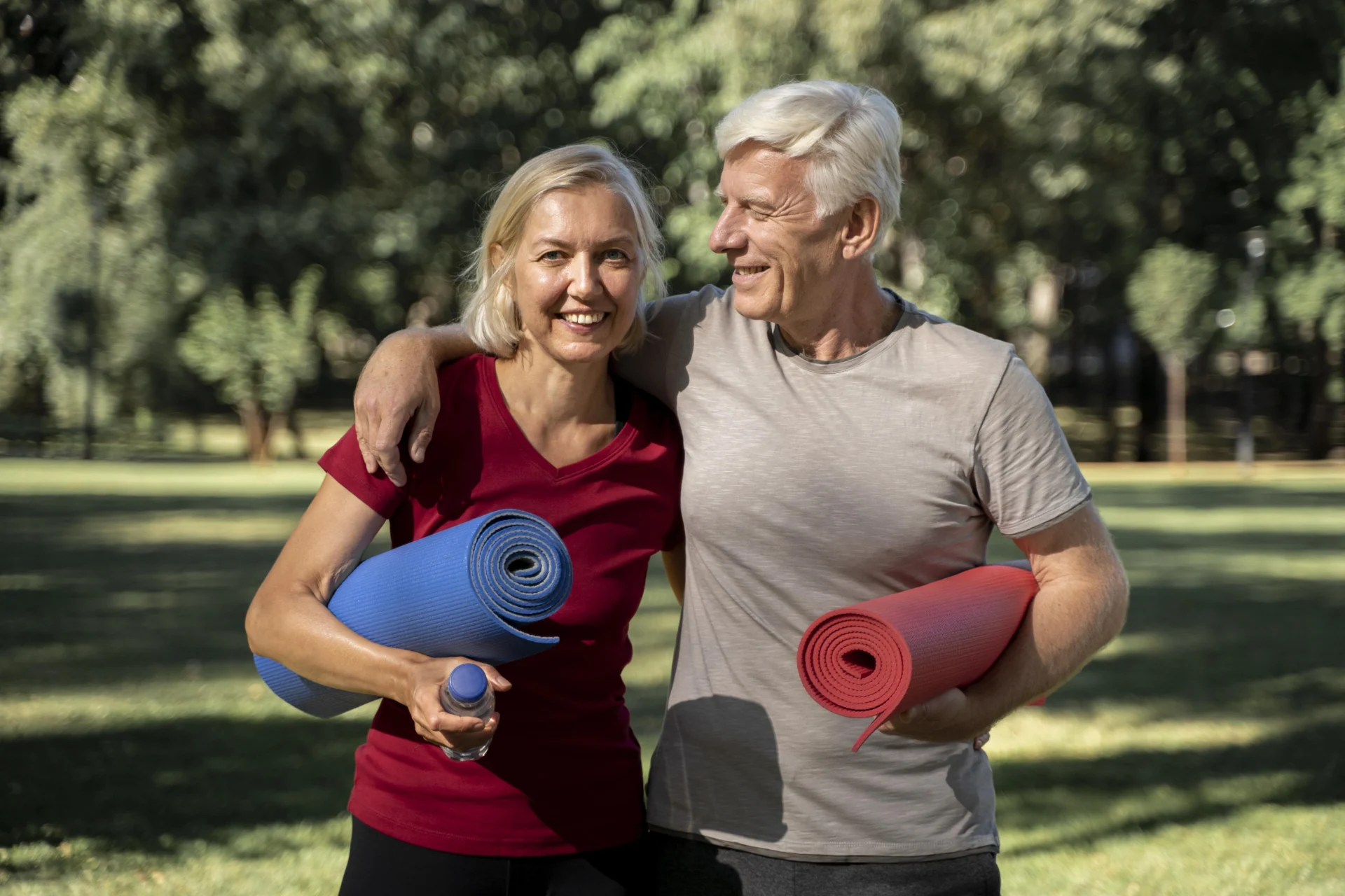 smiley elder couple outdoors with yoga mats water bottle scaled