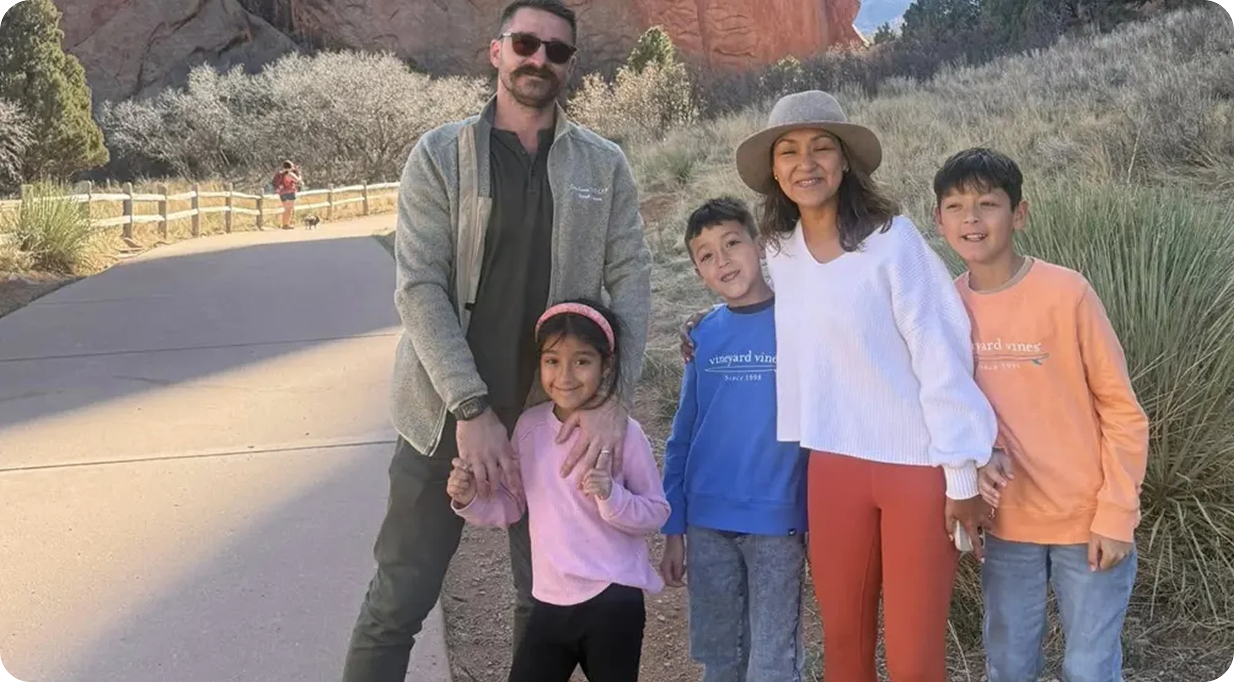 Family of five posing on a trail in a rocky park.