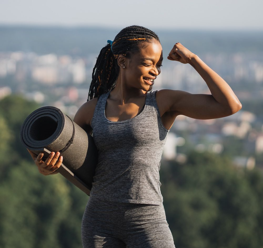 smiling-african-woman-showing-her-biceps-outdoors